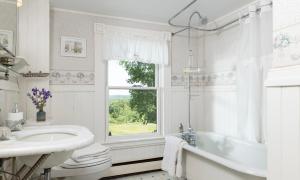 a white bathroom with a tub and a sink and a window at Maguire House Bed and Breakfast in Ashburnham