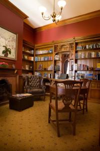 a library with a table and chairs and a couch at Otahuna Lodge in Christchurch