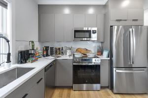 a kitchen with white cabinets and a stainless steel refrigerator at Cambridge Designer Home Harvard MIT Boston in Cambridge