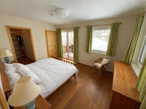 a bedroom with a bed and a chair and windows at Landhaus Alpenblick Tauplitz in Tauplitz