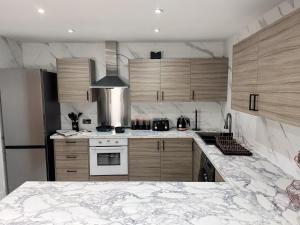 a kitchen with a marble counter top and wooden cabinets at Sunderland Central 2BR Apartments in Sunderland +68 photos