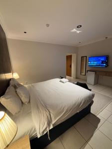 a bedroom with a large bed with a tv on the wall at Alassaf 304 in Sīdī Ḩamzah +3 photos