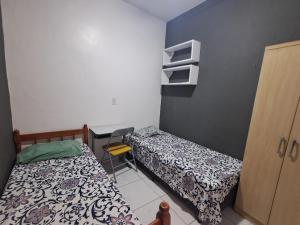 a small room with two beds and a desk at Pousada econômica puc in Porto Alegre