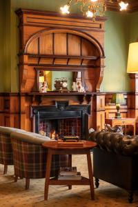 a living room with a fireplace with a couch and a table at Otahuna Lodge in Christchurch