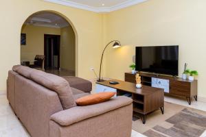 a living room with a couch and a flat screen tv at MAAT Luxury Homes in Accra