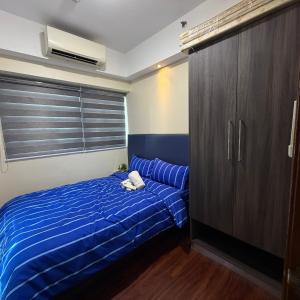 a bedroom with a blue bed and a cabinet at RKJ condotel 2BR in Cupang