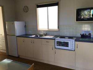 a kitchen with a white refrigerator and a sink at Waters Edge Holiday Park in Lakes Entrance