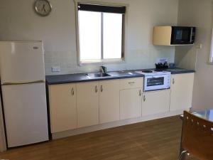 a kitchen with white cabinets and a sink and a refrigerator at Waters Edge Holiday Park in Lakes Entrance +10 photos