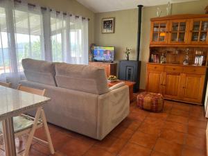 a living room with a couch and a tv at La Cabaña del aviador in Feás
