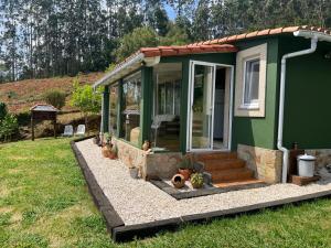a green tiny house in a yard at La Cabaña del aviador in Feás
