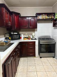 a kitchen with wooden cabinets and a stove at Hospedaje Ejecutivo Toronjal II in La Ceiba
