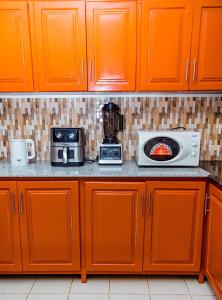 a kitchen with orange cabinets and a microwave at The new home in Moshi