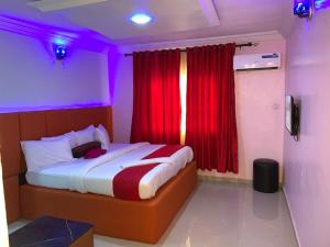 a bedroom with a bed with a red curtain at Diamond Groove Hotel & Suites in Sangotedo