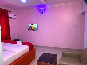 a room with a bed and a tv on a wall at Diamond Groove Hotel & Suites in Sangotedo