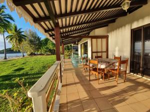 a patio with a table and chairs under a wooden pergola at Hôtel Atiapiti in Opoa