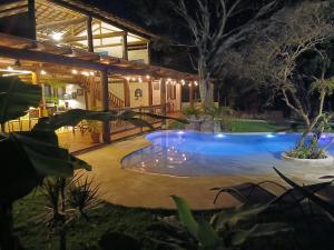 a swimming pool in the yard of a house at night at Vila Natholi Hotel Boutique in Imbassai