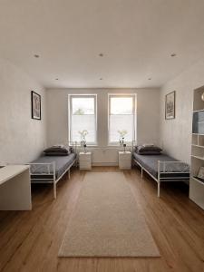 a large room with two beds and two windows at H&R Suite - Bielefeld Central in Bielefeld +6 photos