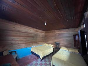 a bedroom with two beds and a wooden wall at Hotel bar y restaurante Millenium Lanquin in Lanquín