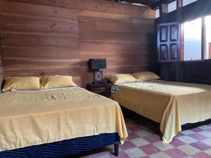 two beds in a room with wooden walls at Hotel bar y restaurante Millenium Lanquin in Lanquín