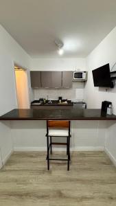 a kitchen with a table and a chair in a room at Palladium Refúgio - 500 metros da Praia, Perto do Shopping, Wi-Fi, Piscina e Garagem in São Vicente