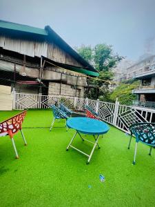 a group of chairs and a blue table on the grass at Mall Rd Murree Ciros Hotel in Murree +4 photos