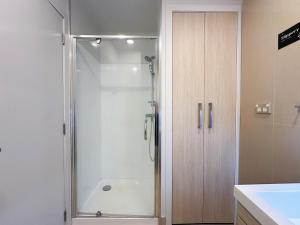 a shower with a glass door in a bathroom at Sky Stars Essential Reserve in Auckland