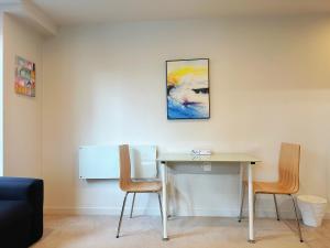 a table with two chairs and a painting on the wall at Sky Stars Essential Reserve in Auckland