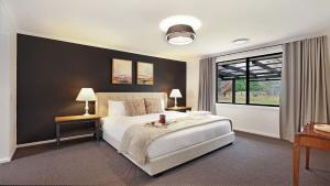 a bedroom with a large white bed and a window at Mirambeena in Berrima