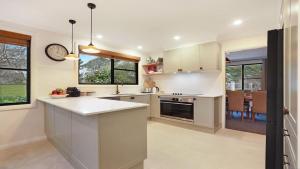 a kitchen with white cabinets and a clock on the wall at Mirambeena in Berrima
