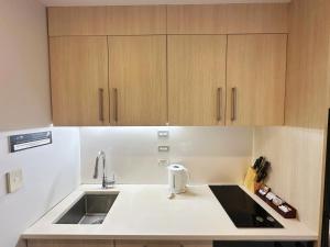 a kitchen with a sink and wooden cabinets at Sky Stars Essential Reserve in Auckland +98 photos