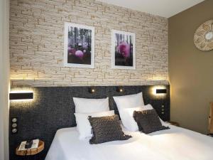 a bedroom with a large bed with two pictures on the wall at ibis Styles Rennes St. Gregoire in Saint-Grégoire +91 photos