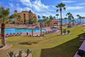 a resort with a swimming pool and palm trees at Princesa de Penasco B208 - Family Beach Getaway in Puerto Peñasco