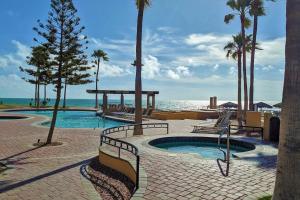 a swimming pool with palm trees and the ocean at Princesa de Penasco B208 - Family Beach Getaway in Puerto Peñasco