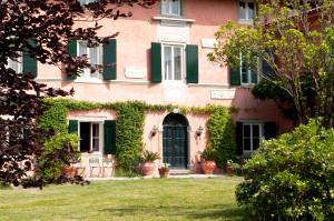 um edifício cor-de-rosa com persianas verdes e um quintal em Tenuta Perusini em Corno di Rosazzo
