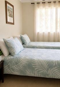 a bedroom with two beds and a window at Seascape Carroll Avenue - close to Mollymook Beach in Mollymook +7 photos
