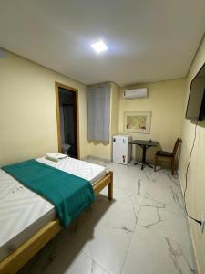 a bedroom with a bed and a table and a television at Oeste Palace-hotel londres in Brasília
