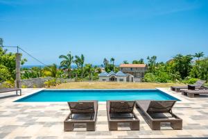 a swimming pool with two lounge chairs and a house at Emotions by Ironshore in Montego Bay