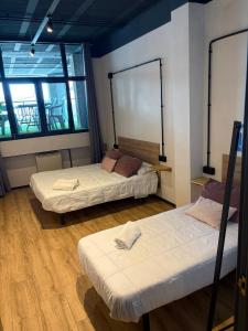 two beds in a room with two windows at Albergue HR in Sarria