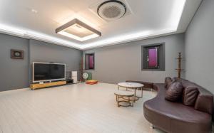 a living room with a couch and a flat screen tv at Andong Win Hotel in Hoam-dong