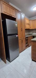 a kitchen with a black refrigerator and wooden cabinets at Pyramids Gardens 2bedroom apartment in ‘Ezbet `Abd el-Ḥamîd +7 photos
