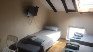 a room with two beds and a tv and a chair at Single Bed Center in Plovdiv