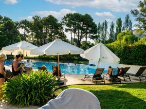 a group of people sitting around a pool with umbrellas at Green Park Departamentos Exclusivos in Punta del Este