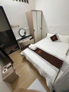 a bedroom with a bed and a desk with a mirror at TUNI Hotel in Long Bình