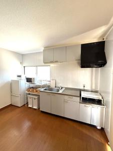 a kitchen with white cabinets and a wooden floor at Flat Dazaifu in Dazaifu