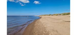 a beach with people walking on the sand and the water at Mysig Lägenhet in Kokkola