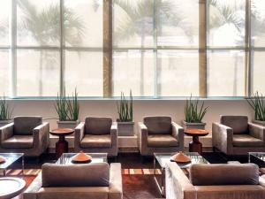 a waiting room with couches and chairs and palm trees at Mercure Salvador Pituba in Salvador