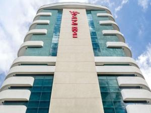 a tall building with a red sign on it at Mercure Salvador Pituba in Salvador