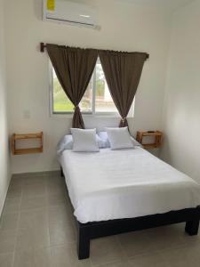 a bedroom with a bed with white sheets and a window at Departamento al lado del Mar in Barra Nueva