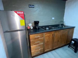 a kitchen with a stainless steel refrigerator and wooden cabinets at Mini Loft en Quezaltepeque in Quezaltepeque