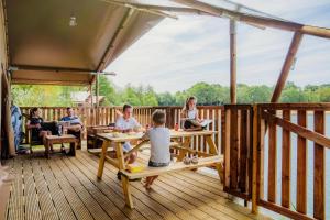 a group of children sitting at tables on a deck at Waterlodge 8 persons #WL02 in Maasbree